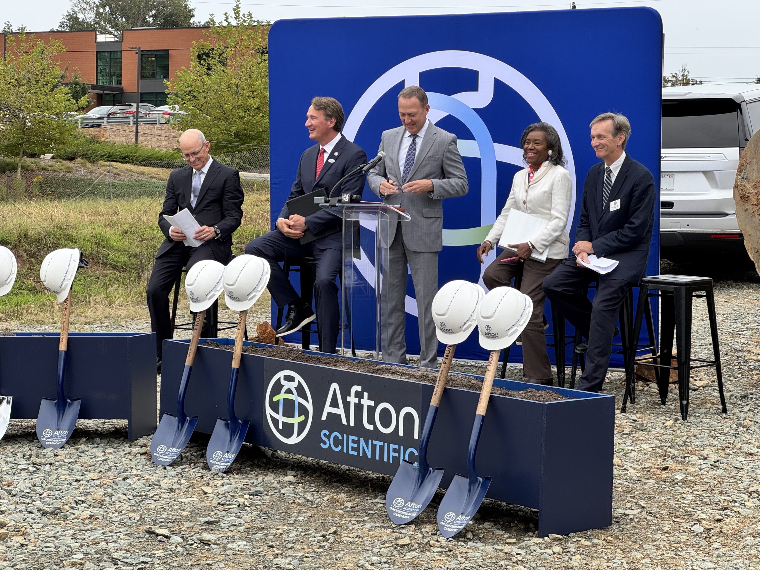 Afton logomark banner with Tom Thorpe, Afton Scientific CEO, Glenn Youngkin, Governor of Virginia and Winsome Earle-Sears, Lieutenant Governor of Virginia along with representatives from Albemarle County prepare for groundbreaking ceremony.